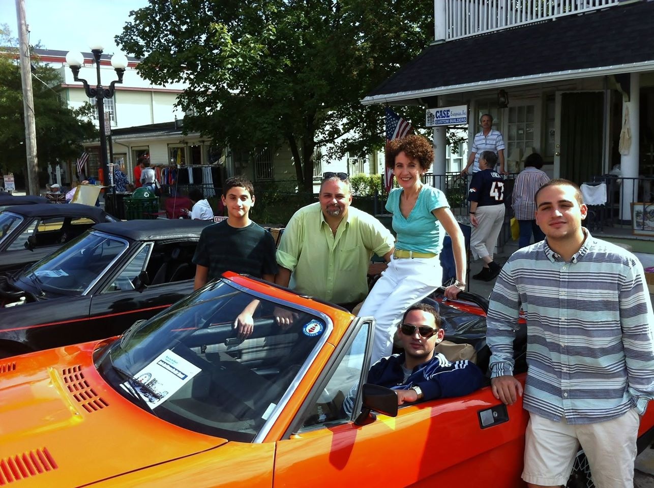 group of people sitting/around orange car